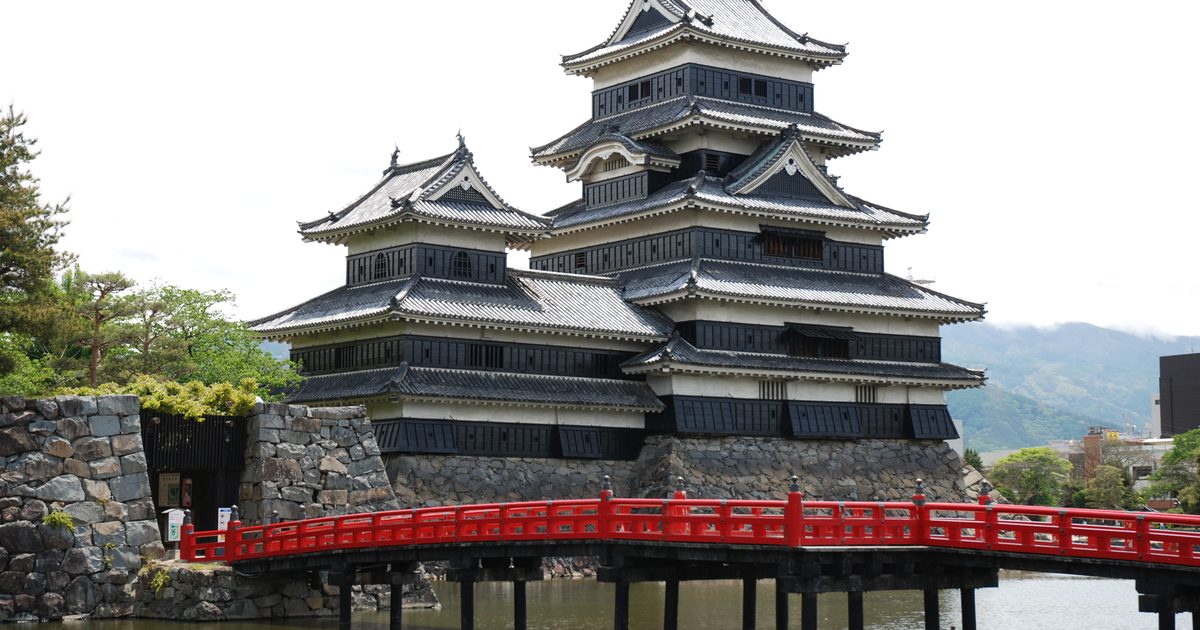 Der schwarz-weiße Hauptbergfried von Matsumoto Castle mit seinen verbundenen Türmen, vom Burggraben aus gesehen